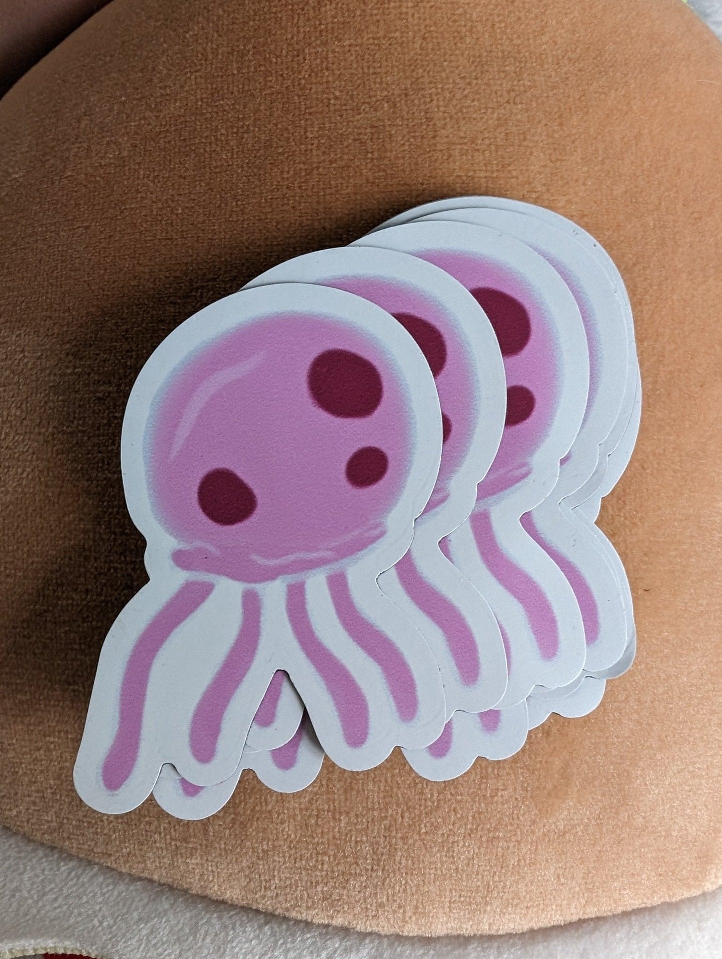 stack of pink jellyfish magnets fanned out, digitally drawn, on a soft light brown background