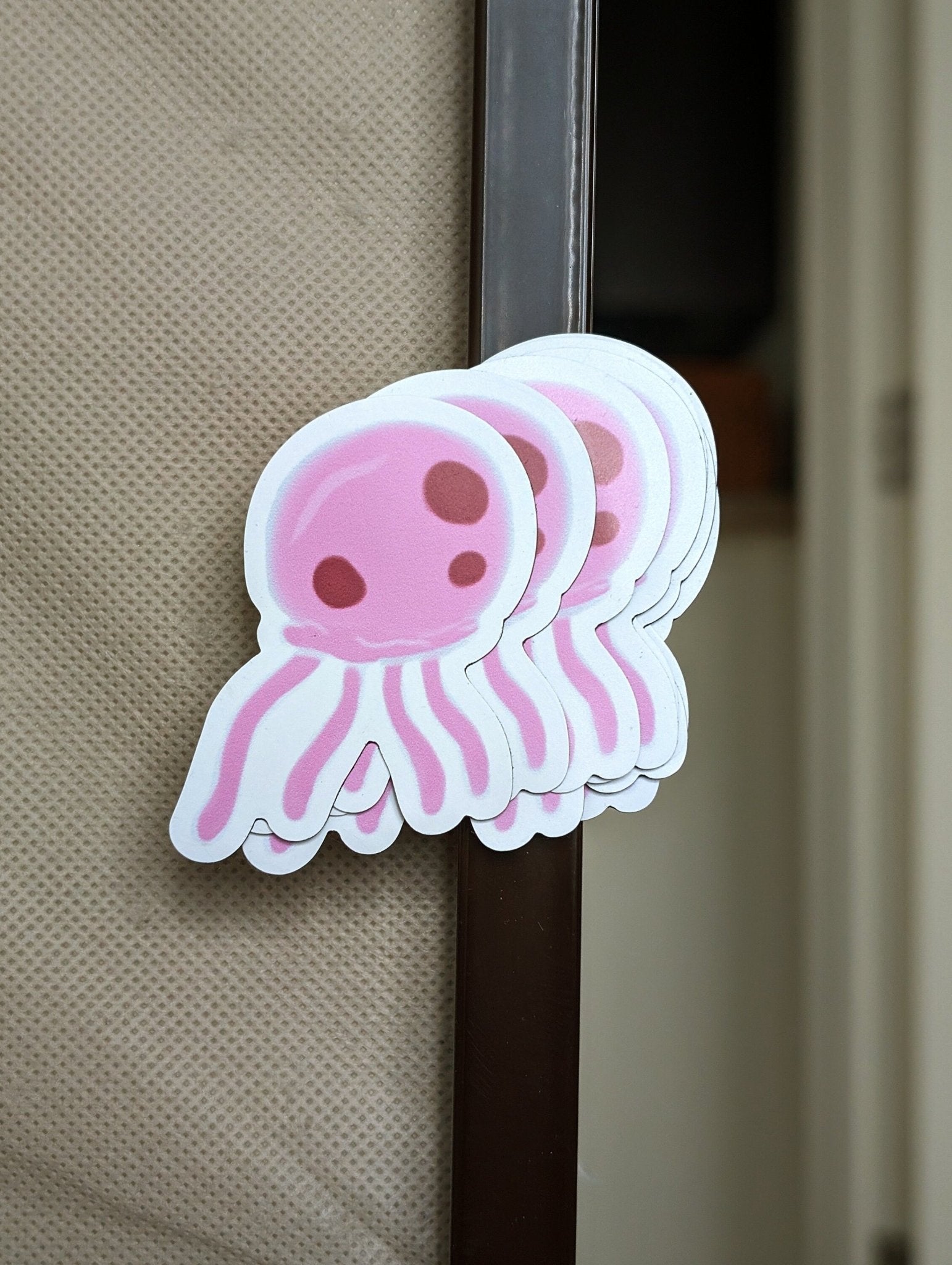 stack of pink jellyfish magnets fanned out, digitally drawn, attached to a metal dresser frame