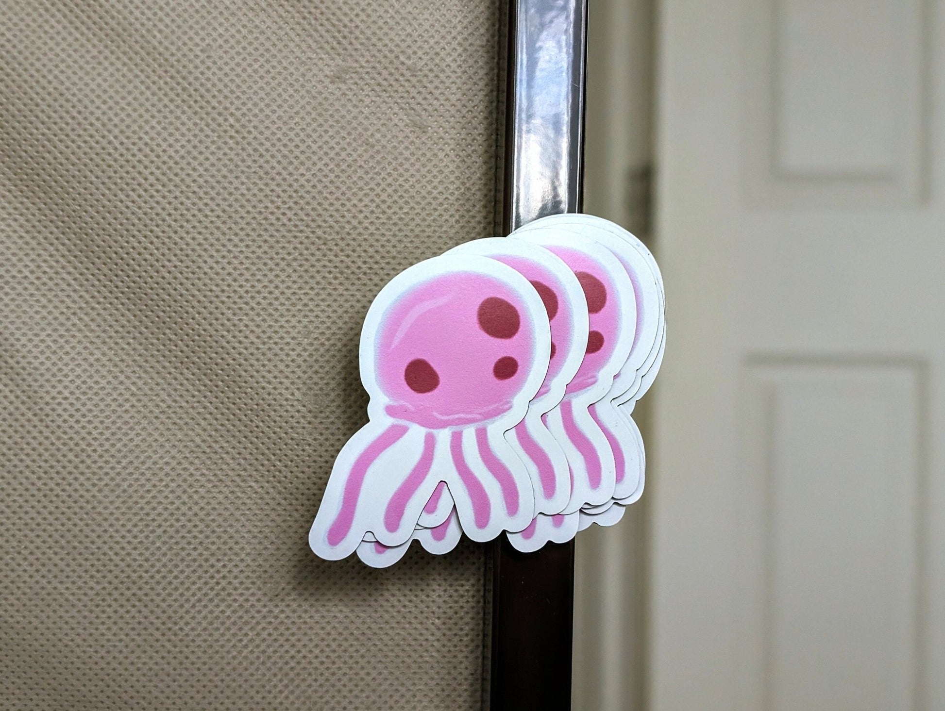 stack of pink jellyfish magnets fanned out, digitally drawn, attached to a metal dresser frame