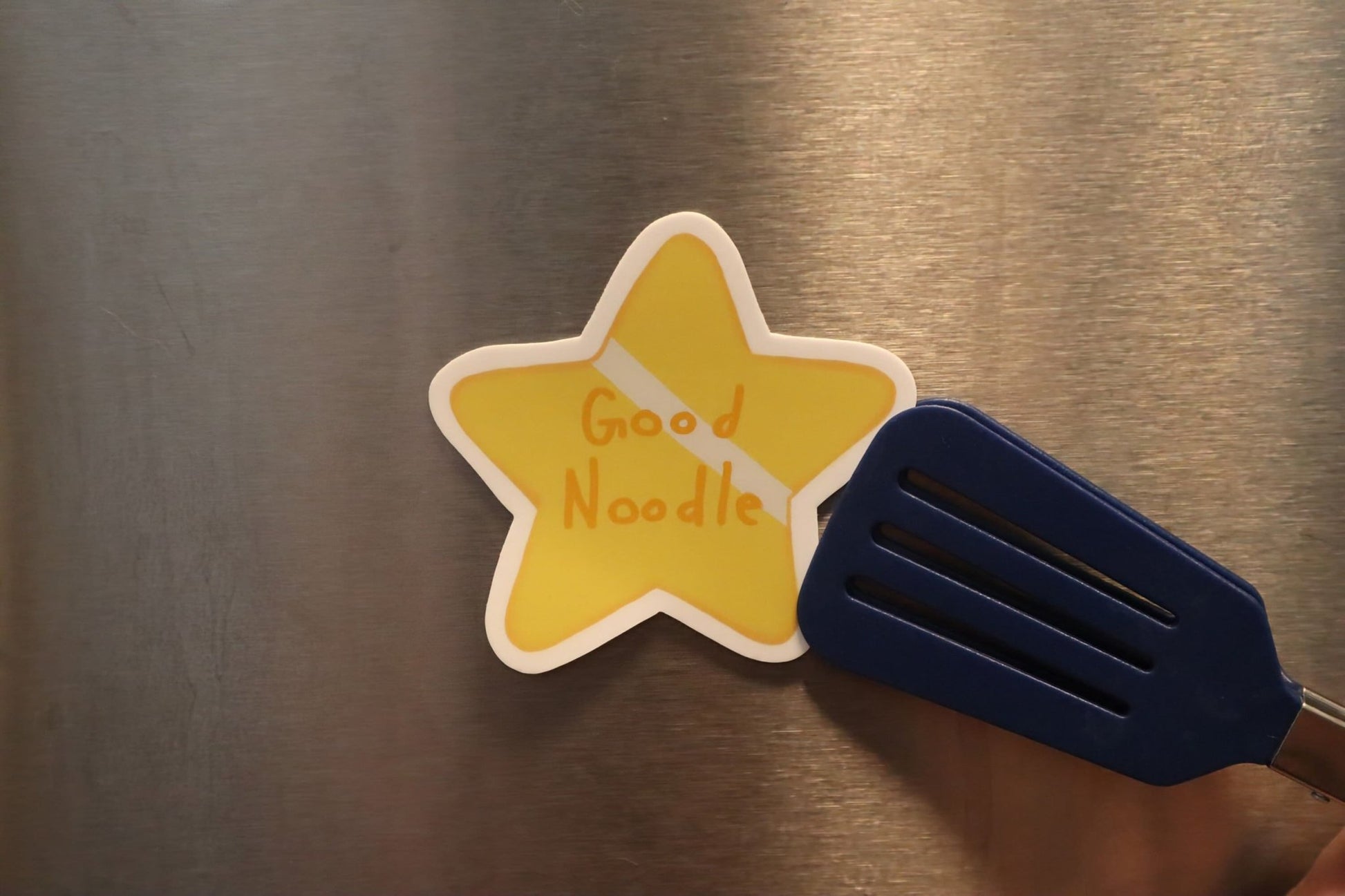 gold star sticker held up to a magnetic surface by mini spatula